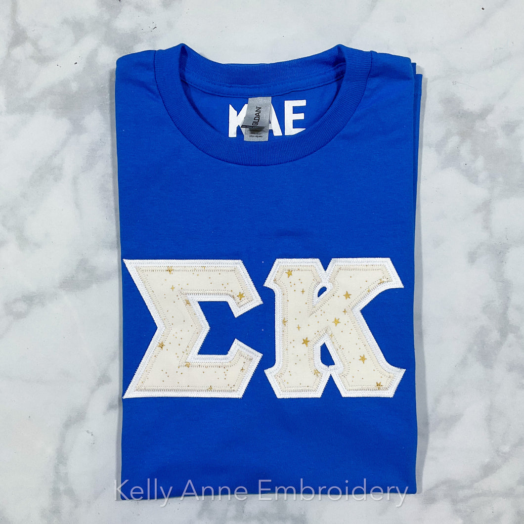 Cream Metallic Stars Greek Letters with White Border on Royal Blue T-Shirt